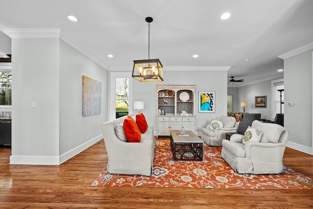 living room with crown molding, ceiling fan with notable chandelier, and hardwood / wood-style flooring