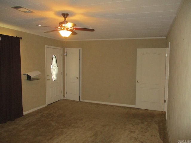 carpeted foyer entrance with visible vents, baseboards, ceiling fan, and crown molding