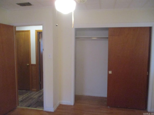 unfurnished bedroom featuring visible vents, wood finished floors, and a closet