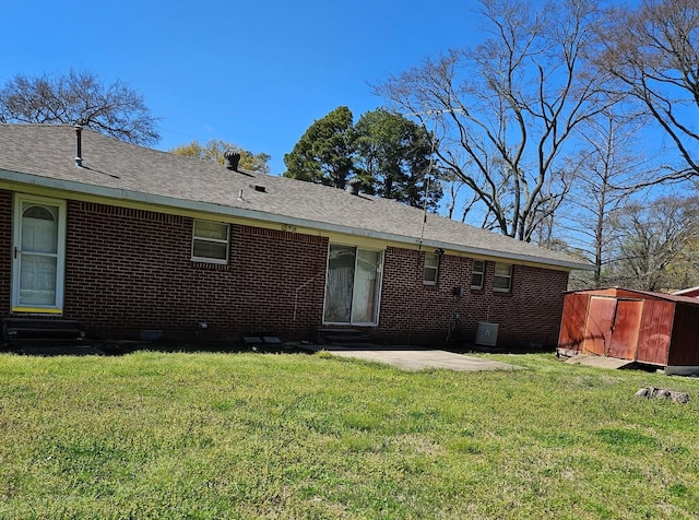 rear view of house featuring brick siding, a lawn, and entry steps