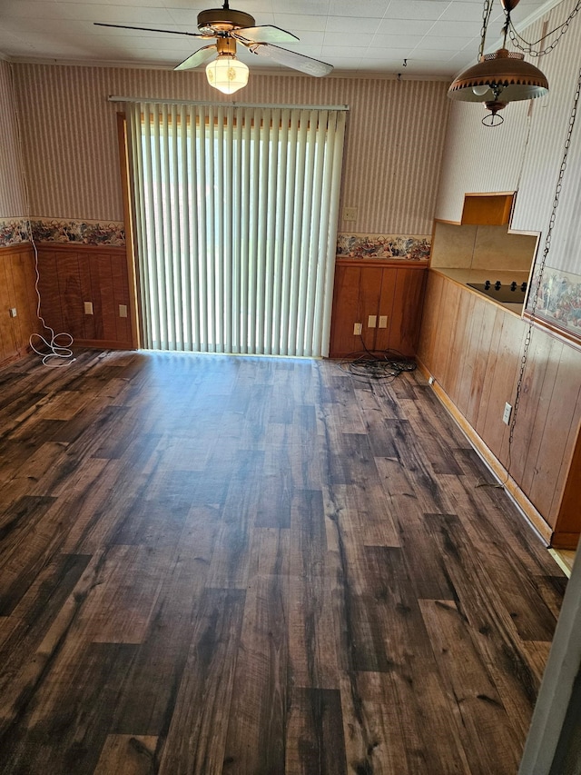 interior space featuring a wainscoted wall, dark wood-type flooring, and ceiling fan