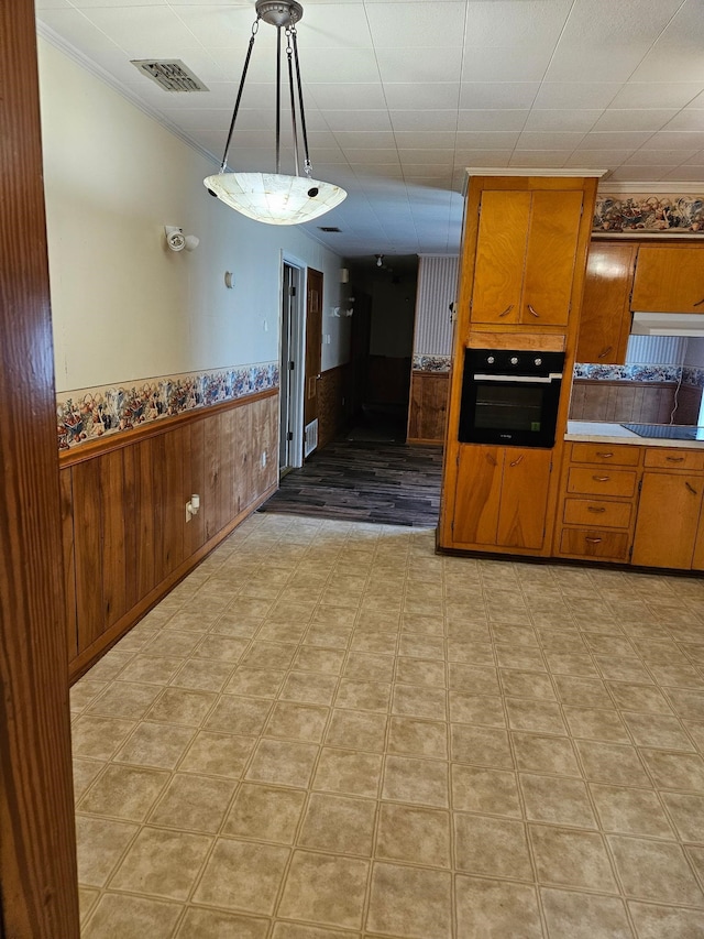 kitchen with hanging light fixtures, wood walls, and black appliances