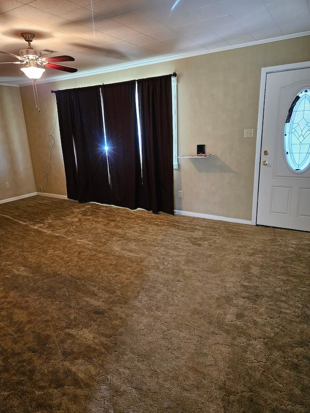 carpeted entrance foyer with a ceiling fan, baseboards, and ornamental molding