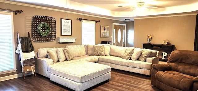 living room featuring dark hardwood / wood-style flooring, a tray ceiling, and ceiling fan