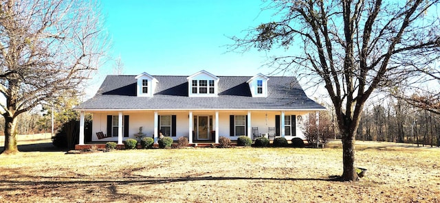 cape cod house featuring a porch and a front lawn