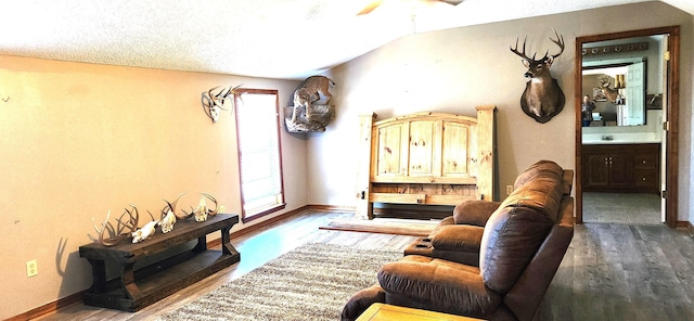 living room featuring hardwood / wood-style floors, lofted ceiling, sink, ceiling fan, and a textured ceiling