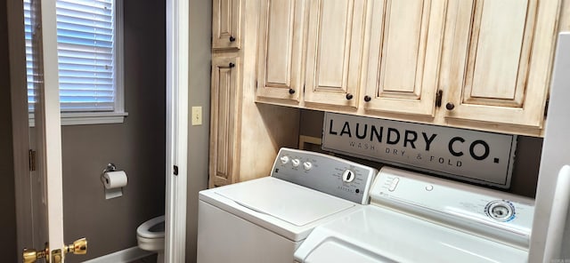 clothes washing area with cabinets and washing machine and dryer