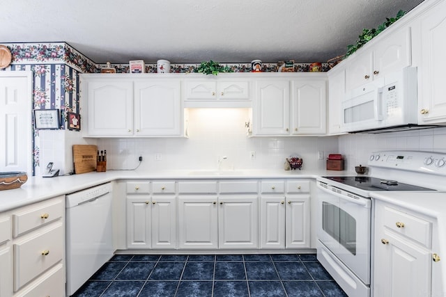 kitchen with sink, white appliances, tasteful backsplash, white cabinets, and dark tile patterned flooring