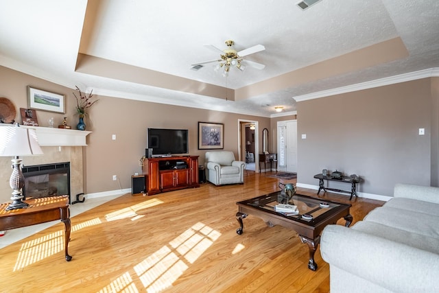 living room with crown molding, a premium fireplace, hardwood / wood-style flooring, and a raised ceiling