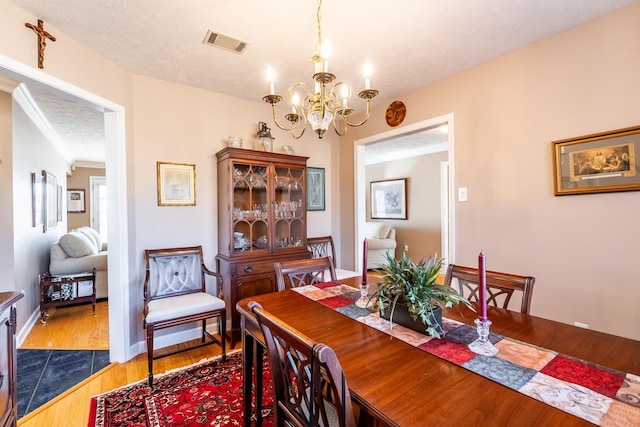 dining room featuring dark hardwood / wood-style flooring, a chandelier, and a textured ceiling