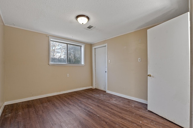 unfurnished room with crown molding, dark wood-type flooring, and a textured ceiling