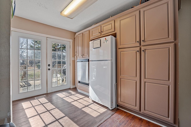 kitchen with french doors, dark hardwood / wood-style flooring, white fridge, and a textured ceiling