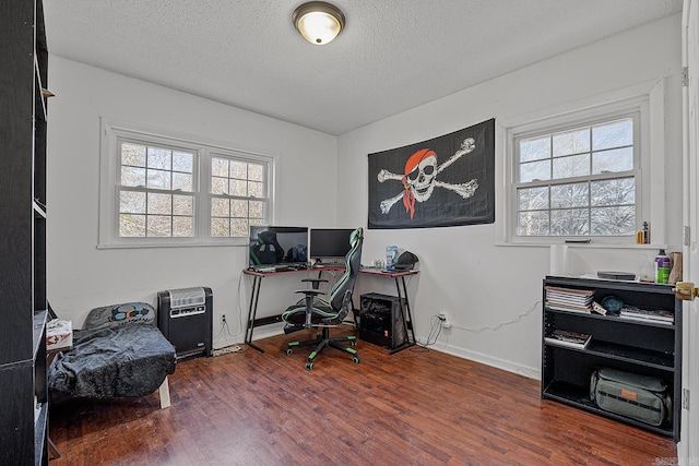 office featuring a textured ceiling, dark wood-type flooring, and a healthy amount of sunlight