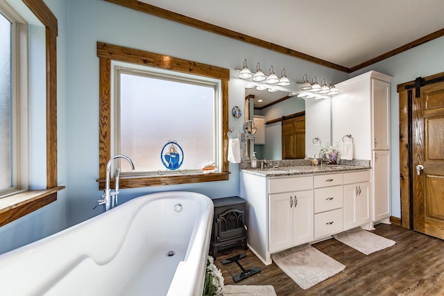 bathroom with ornamental molding, wood-type flooring, a bath, and vanity