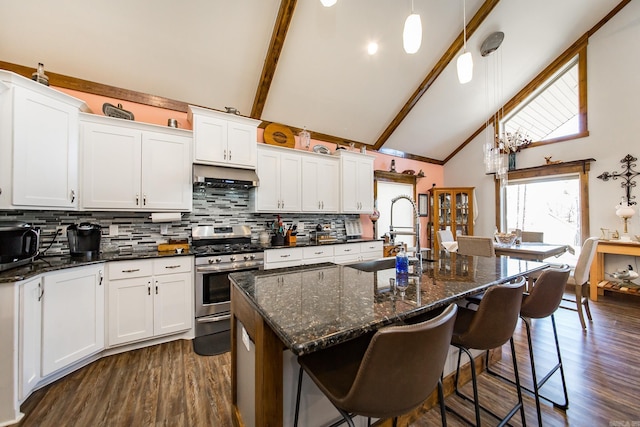 kitchen featuring pendant lighting, appliances with stainless steel finishes, white cabinetry, a kitchen island with sink, and beamed ceiling