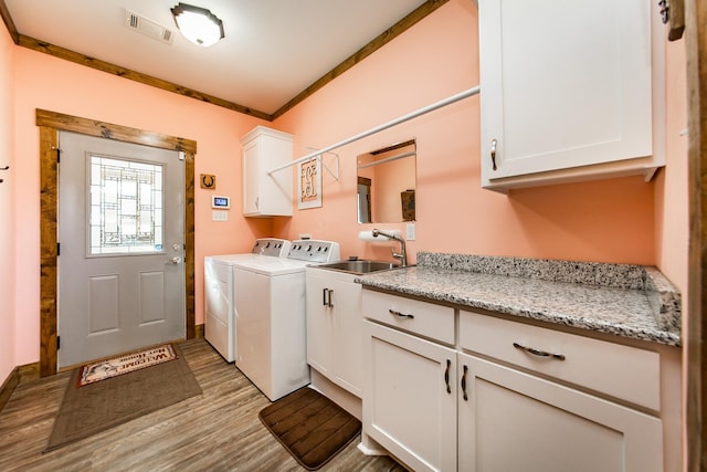 laundry area featuring sink, cabinets, ornamental molding, washing machine and dryer, and light hardwood / wood-style flooring