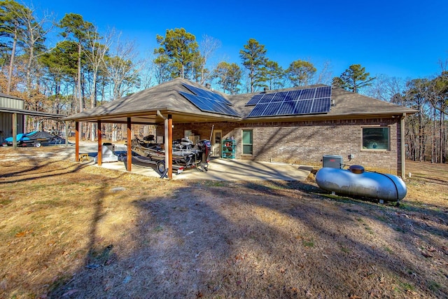 back of house with cooling unit, a patio area, and solar panels