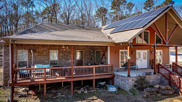 back of house with a deck and solar panels