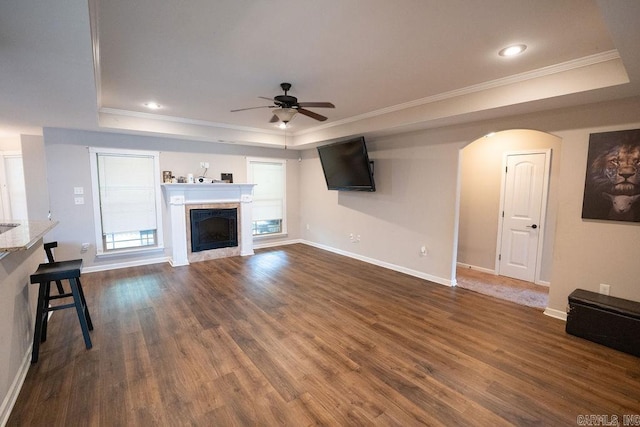 unfurnished living room with crown molding, ceiling fan, dark hardwood / wood-style flooring, and a raised ceiling