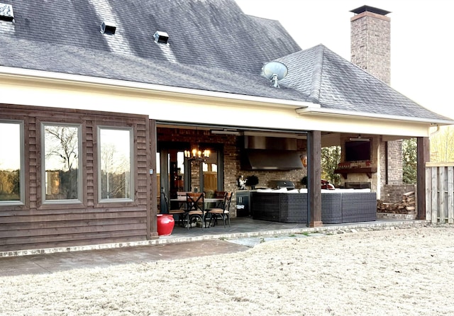 rear view of property featuring a patio and an outdoor living space with a fireplace