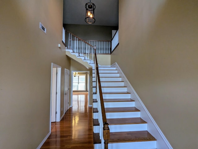 stairway with a towering ceiling and hardwood / wood-style floors