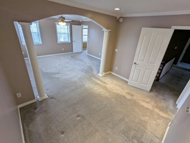 carpeted empty room featuring ornamental molding, ceiling fan, and ornate columns