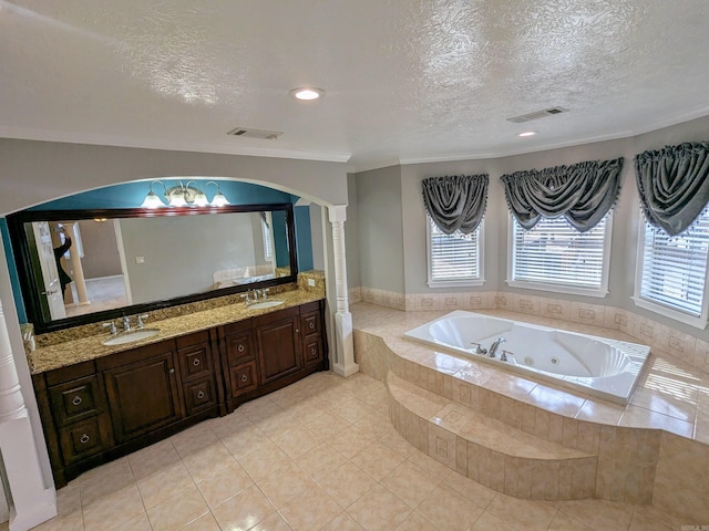 bathroom with tiled tub, decorative columns, vanity, a textured ceiling, and tile patterned floors