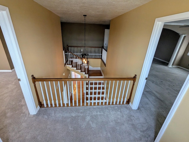 stairway with carpet floors and a textured ceiling