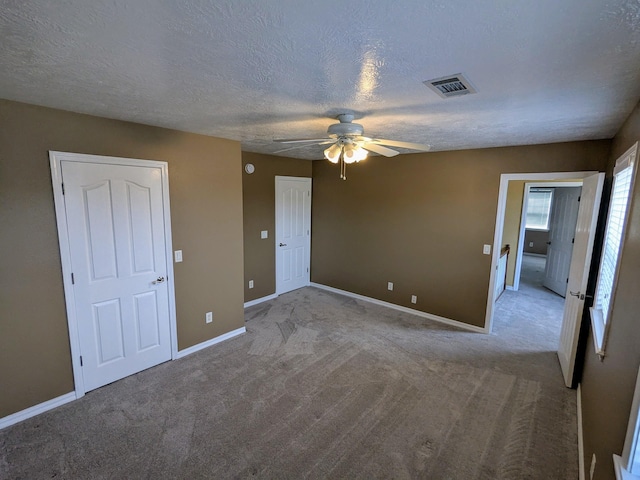 unfurnished bedroom with light colored carpet, a textured ceiling, and ceiling fan