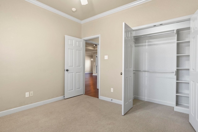 unfurnished bedroom featuring crown molding, ceiling fan, carpet flooring, and a closet