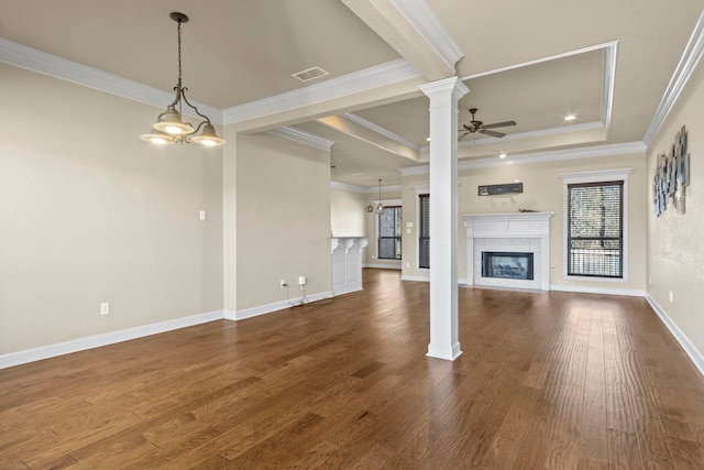 unfurnished living room featuring ornate columns, a tile fireplace, ceiling fan with notable chandelier, a raised ceiling, and crown molding