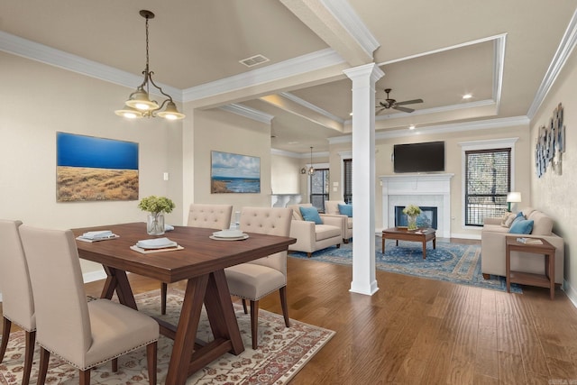 dining space featuring ornate columns, crown molding, dark hardwood / wood-style floors, a raised ceiling, and ceiling fan with notable chandelier