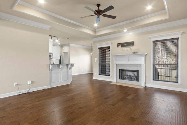 unfurnished living room with ornamental molding, ceiling fan, a fireplace, and a tray ceiling