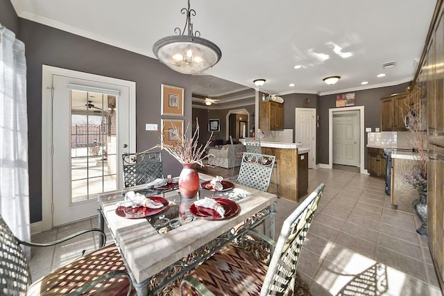 tiled dining area featuring crown molding, ceiling fan, and sink