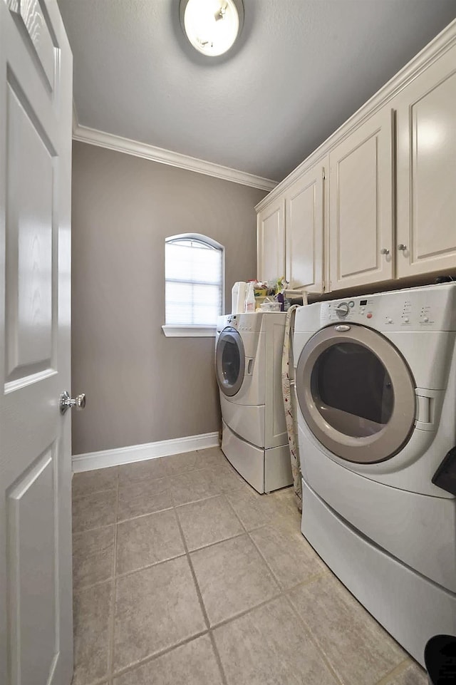 washroom featuring ornamental molding, cabinets, washing machine and clothes dryer, and light tile patterned flooring