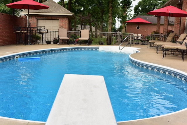 view of pool with a diving board and a patio area