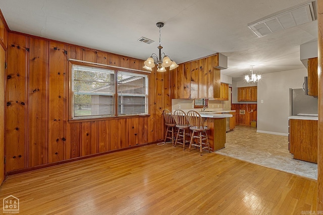 kitchen with pendant lighting, wooden walls, and a notable chandelier