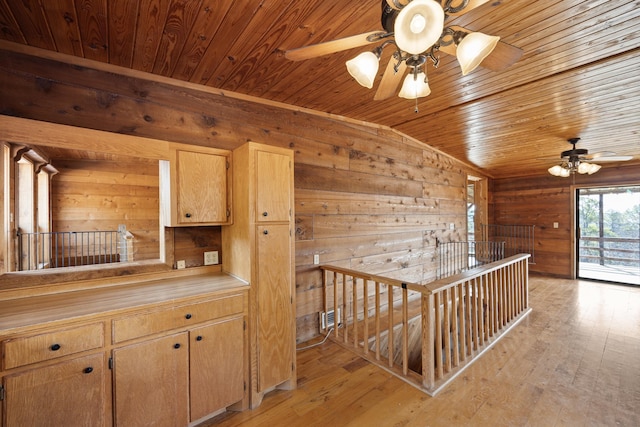 hallway with vaulted ceiling, wooden ceiling, light wood-type flooring, and wood walls