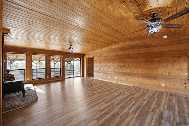 unfurnished living room with lofted ceiling, wood walls, wood-type flooring, a wood stove, and wooden ceiling