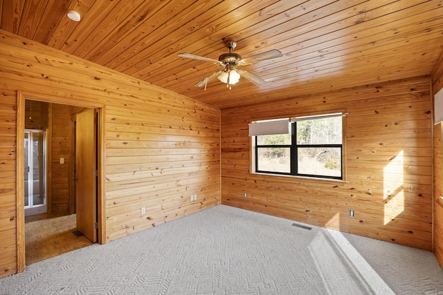 carpeted empty room with ceiling fan, wood ceiling, and wood walls