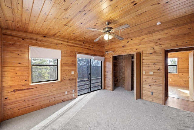 unfurnished bedroom featuring ceiling fan, wooden walls, carpet, and wooden ceiling