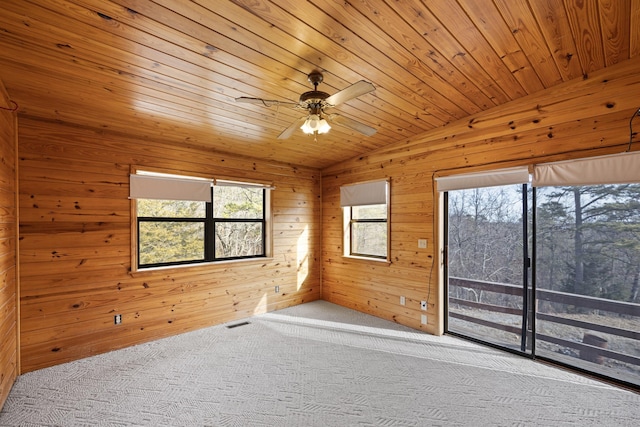 empty room with vaulted ceiling, wood walls, carpet flooring, ceiling fan, and wood ceiling