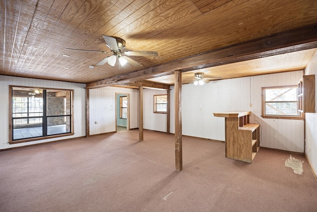 basement featuring carpet, wooden ceiling, ceiling fan, and wood walls