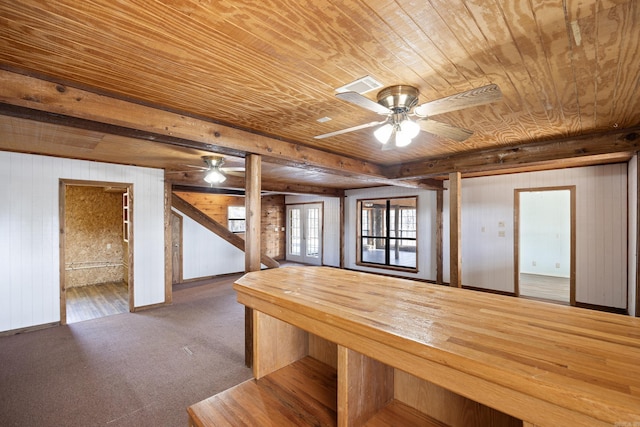 unfurnished dining area featuring wood ceiling, ceiling fan, carpet, french doors, and wood walls