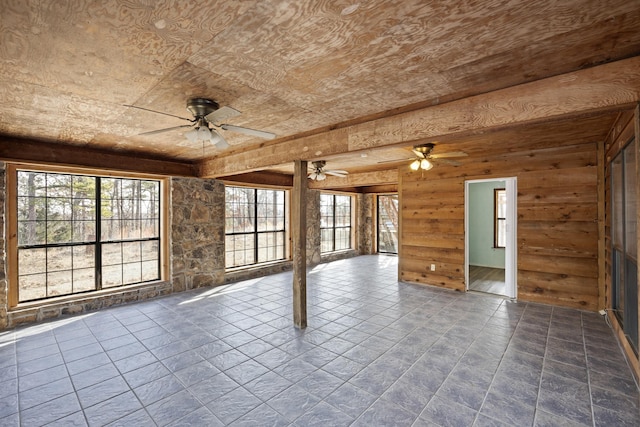 unfurnished room with ceiling fan and wood walls