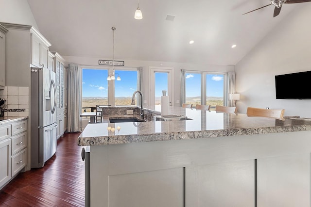 kitchen featuring stainless steel refrigerator with ice dispenser, light stone countertops, pendant lighting, and decorative backsplash