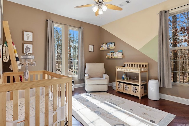 bedroom featuring a nursery area, ceiling fan, dark hardwood / wood-style flooring, and vaulted ceiling