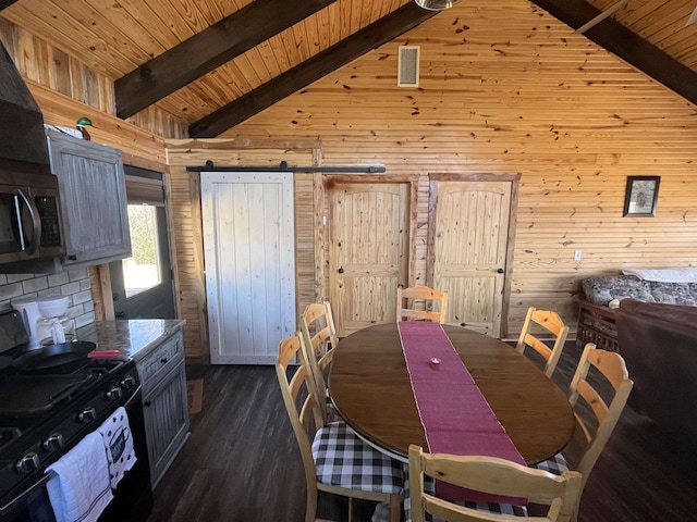 dining space featuring beamed ceiling, wooden walls, wood ceiling, and a barn door