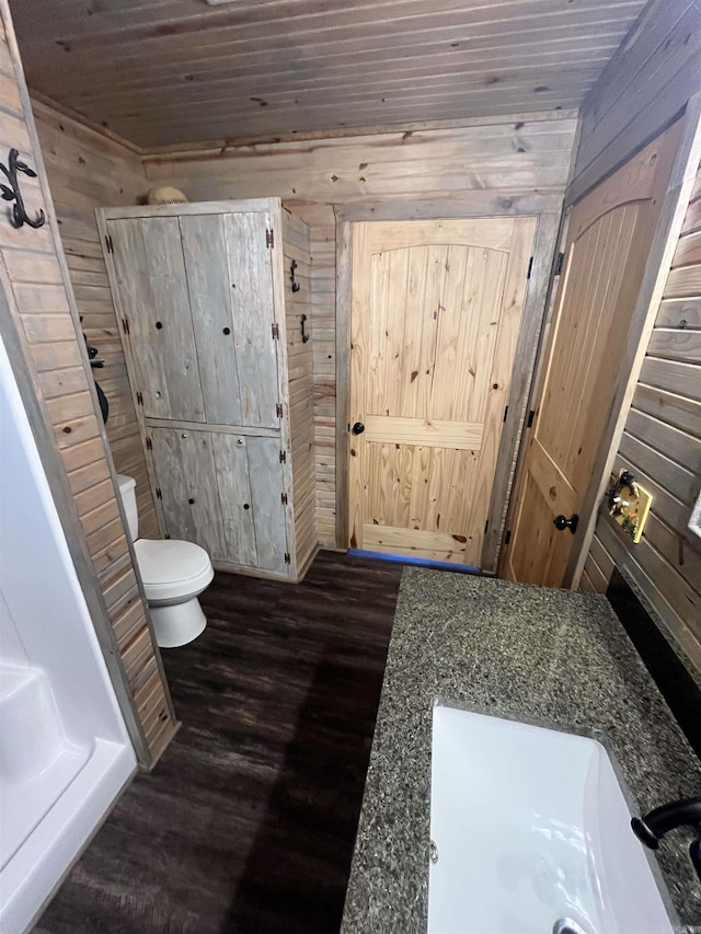 bathroom with toilet, sink, wood-type flooring, wooden ceiling, and wooden walls