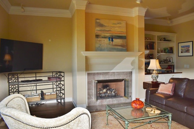 living room featuring a tiled fireplace, ornamental molding, and built in features